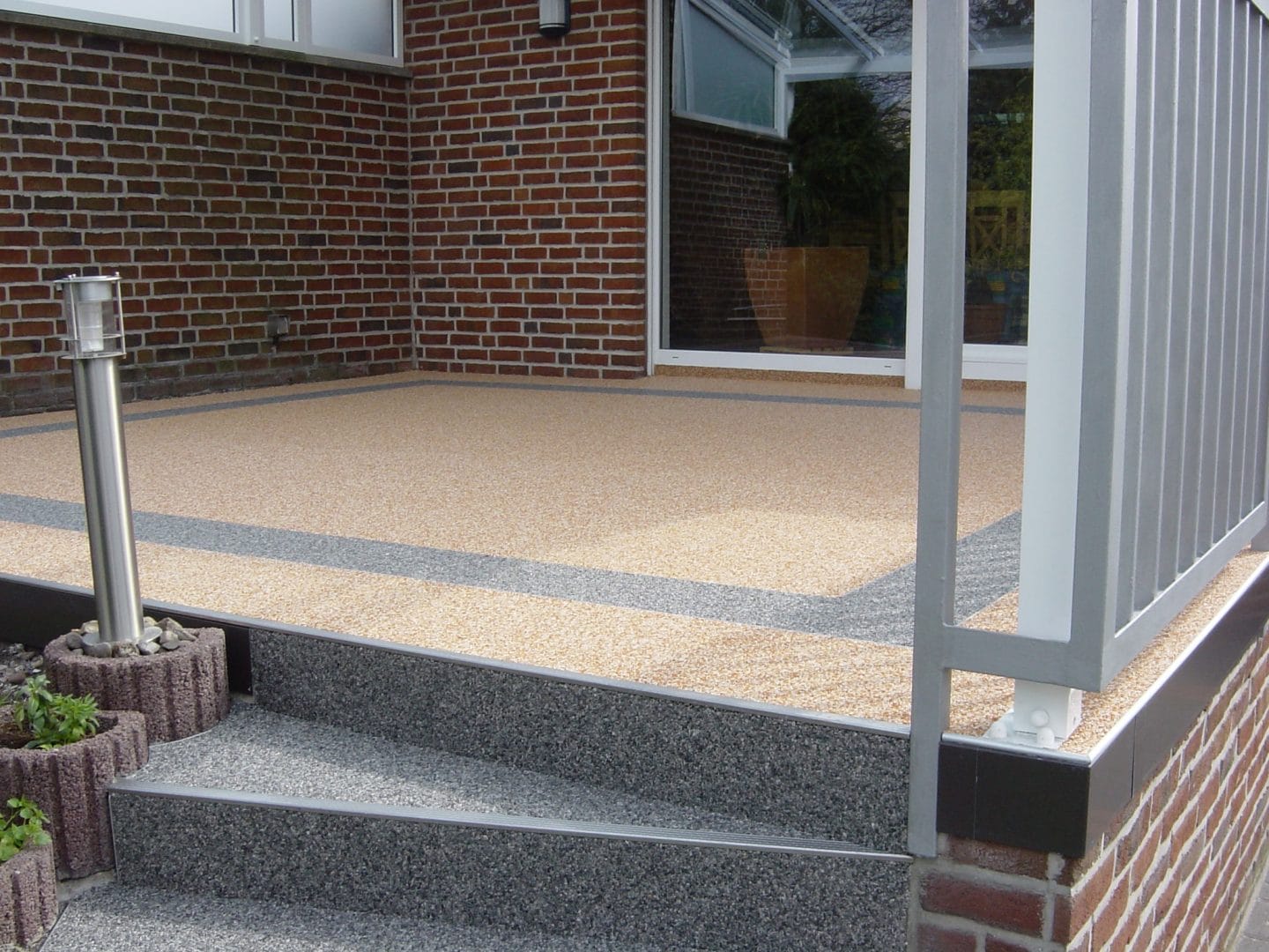 Neuer grau mehlierter Treppenaufgang zu einer Terrasse mit neuem braun mehlierten Boden.